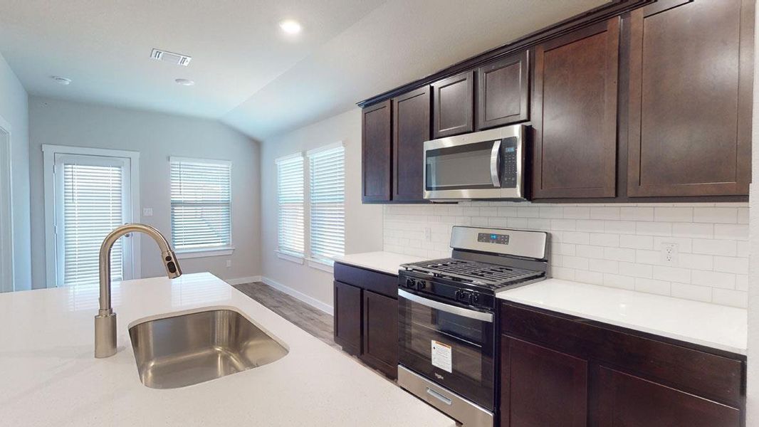 Culinary creations come to life in this kitchen, featuring an island sink and abundant cabinet storage. Culinary creations come to life in this kitchen, featuring an island sink and abundant cabinet storage.