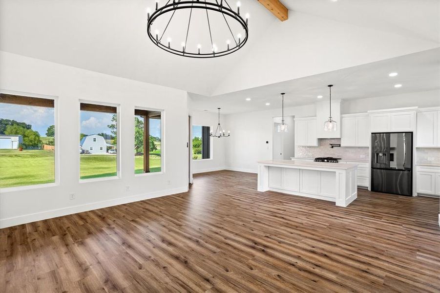 Kitchen with white cabinets, open floor plan, a chandelier, a center island, and beam ceiling Kitchen with white cabinets, open floor plan, a chandelier, a center island, and beam ceiling