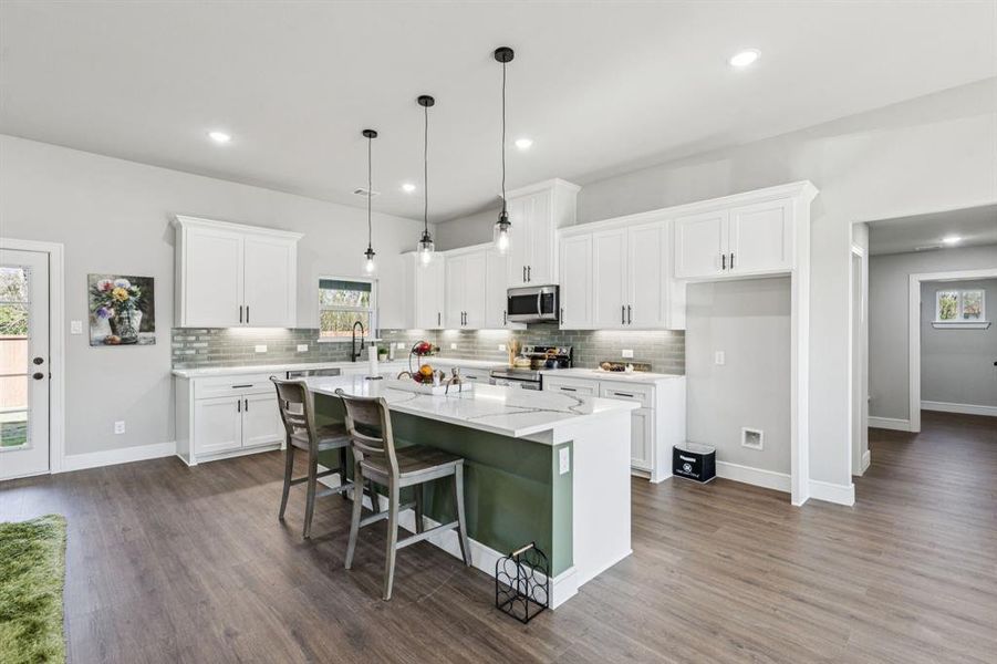 Kitchen with a breakfast bar area, white cabinetry, hanging light fixtures, a kitchen island, and stainless steel appliances