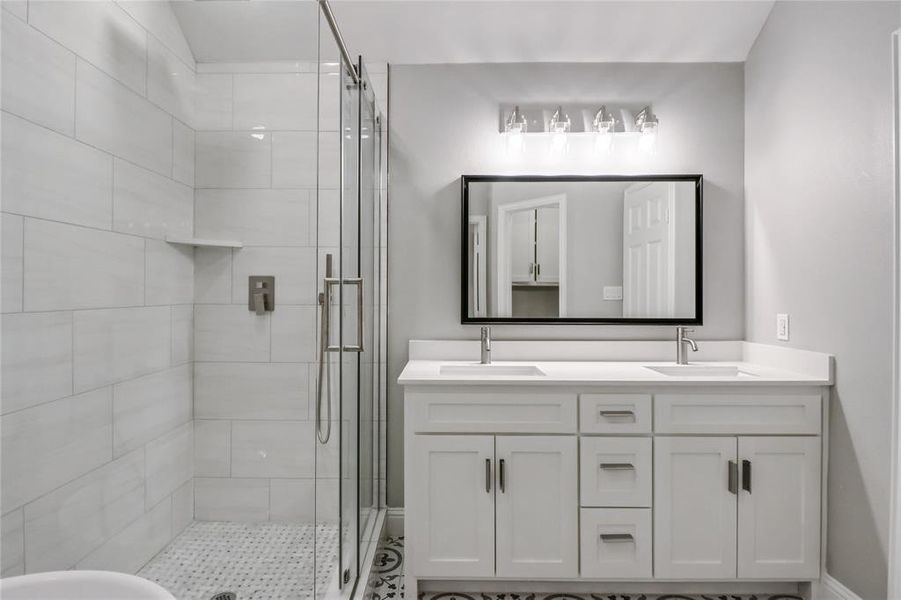 Bathroom featuring dual vanity and a shower with door