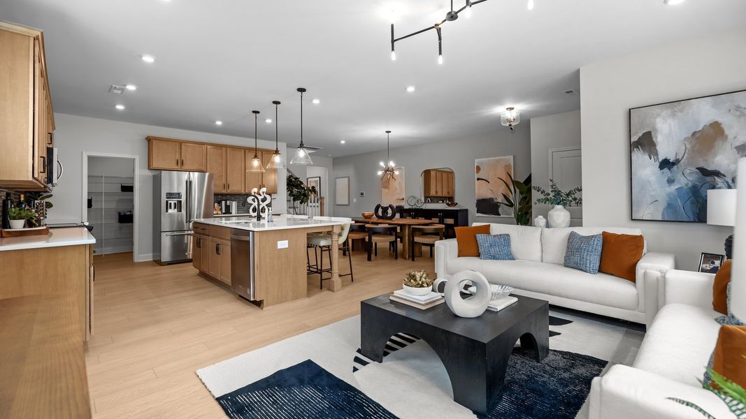Open-concept family room, kitchen, and dining area with premium lighting, in the Adaline Design by DRB Homes Charlotte, NC