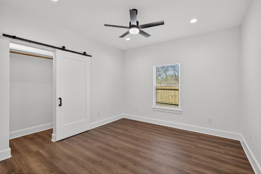 Unfurnished bedroom featuring recessed lighting, dark wood-style flooring, ceiling fan, and a barn door Unfurnished bedroom featuring recessed lighting, dark wood-style flooring, ceiling fan, and a barn door