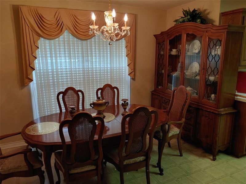 Dining area featuring a chandelier, a large window with draped valance, and patterned flooring