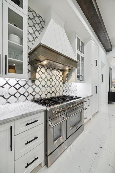 Gorgeous backsplash behind a gas stove. All appliances are stainless-steel Gorgeous backsplash behind a gas stove. All appliances are stainless-steel