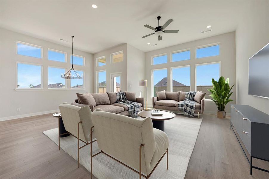 Spacious living area featuring high ceilings, extensive window arrays, recessed lighting, wood-finish flooring, and a modern ceiling fan