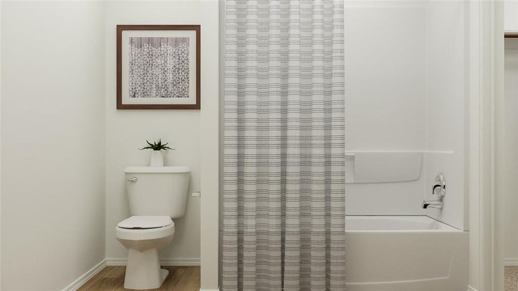 Bathroom featuring toilet, hardwood / wood-style floors, and shower / tub combo with curtain