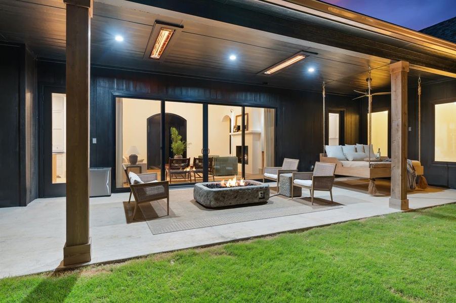 Rear view of house featuring a yard, an outdoor living space with a fire pit, and a patio area