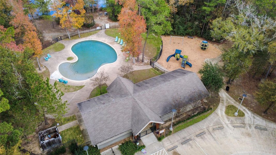 Resort-style living at its finest! This aerial view captures the beach-entry community pool, shaded pavilion, and a modern playground area for family fun.