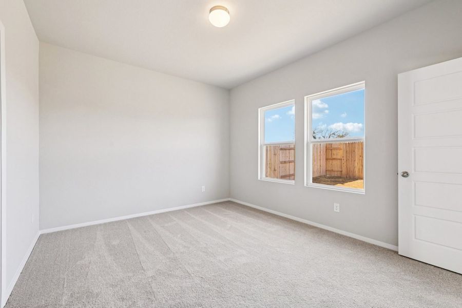 Image of a primary bedroom with grey walls, tan carpeting, two windows and white trim