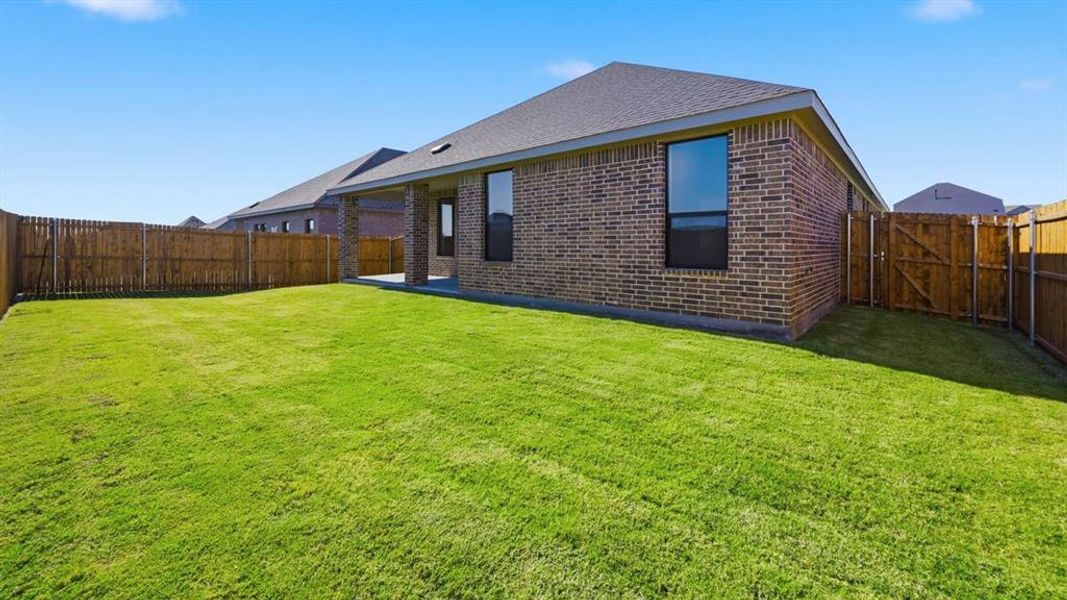 Back of property featuring brick siding, a fenced backyard, a patio area, and a shingled roof Back of property featuring brick siding, a fenced backyard, a patio area, and a shingled roof
