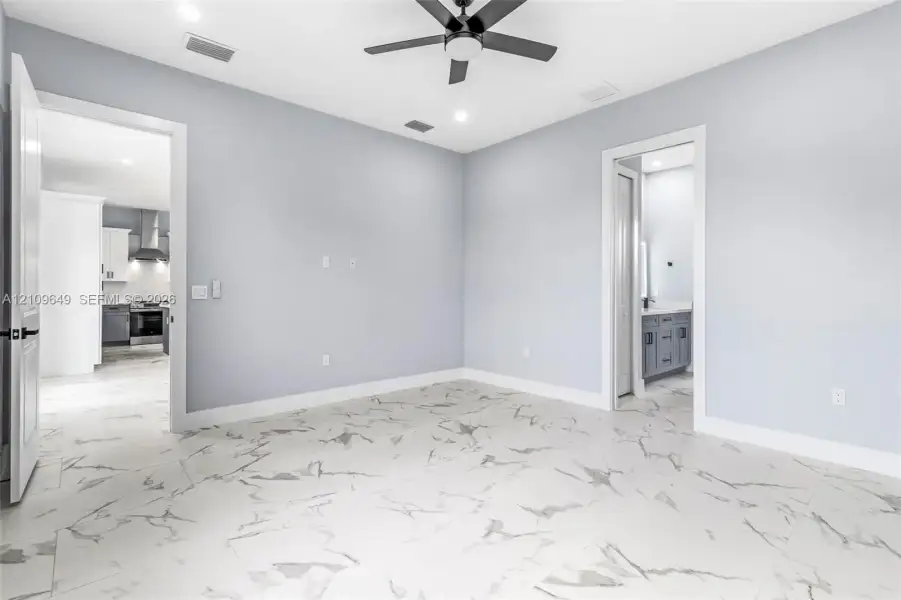 Room featuring large-format tile flooring with a veined pattern, recessed ceiling lighting, and a dark-finish ceiling fan