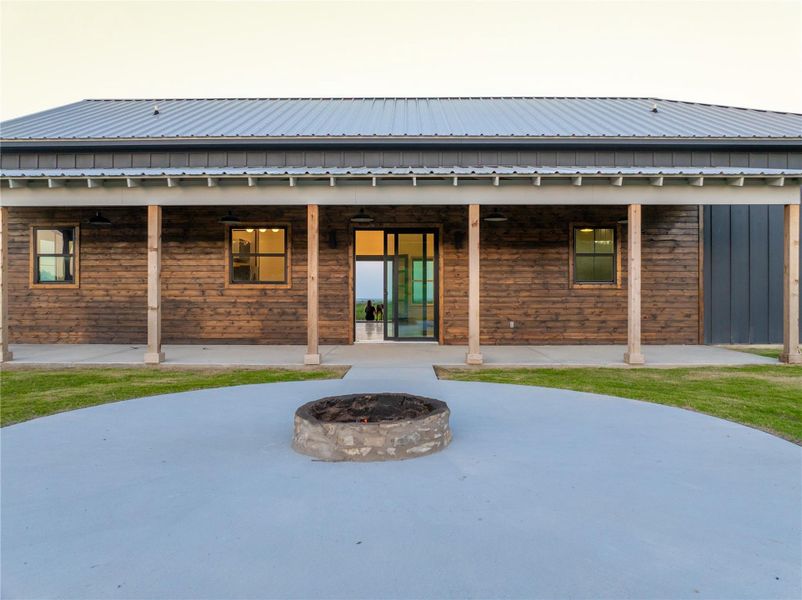 Back of property with a patio area, a fire pit, and a metal roof