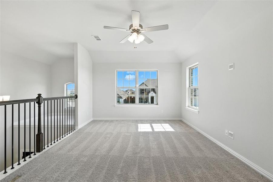 Spare room featuring carpet floors, ceiling fan, and lofted ceiling Spare room featuring carpet floors, ceiling fan, and lofted ceiling
