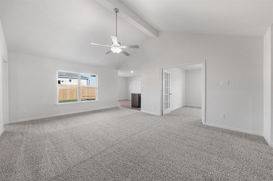 Unfurnished living room featuring carpet, beam ceiling, ceiling fan, and high vaulted ceiling