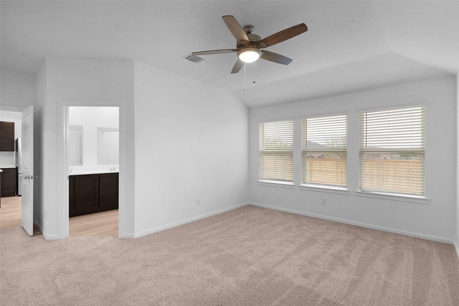 Unfurnished room featuring light colored carpet, ceiling fan, and vaulted ceiling