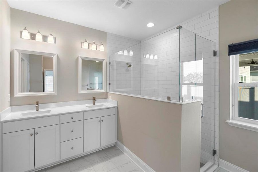 Double vanities, abundant natural light, and upgraded floor-to-ceiling subway tile elevate this bath suite, making it truly unique and rich in thoughtful details.