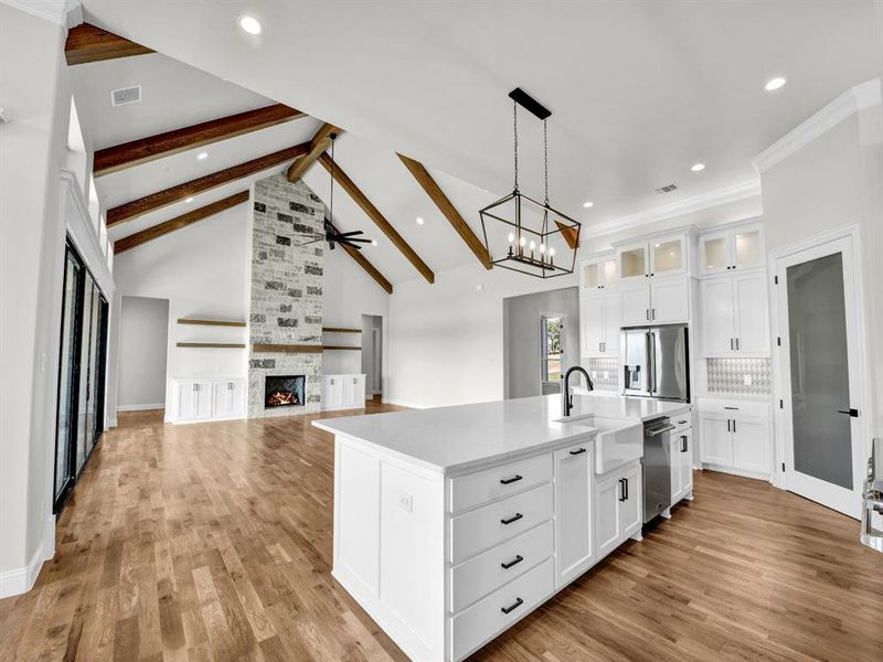 Kitchen with white cabinetry, light hardwood / wood-style floors, appliances with stainless steel finishes, and an island with sink