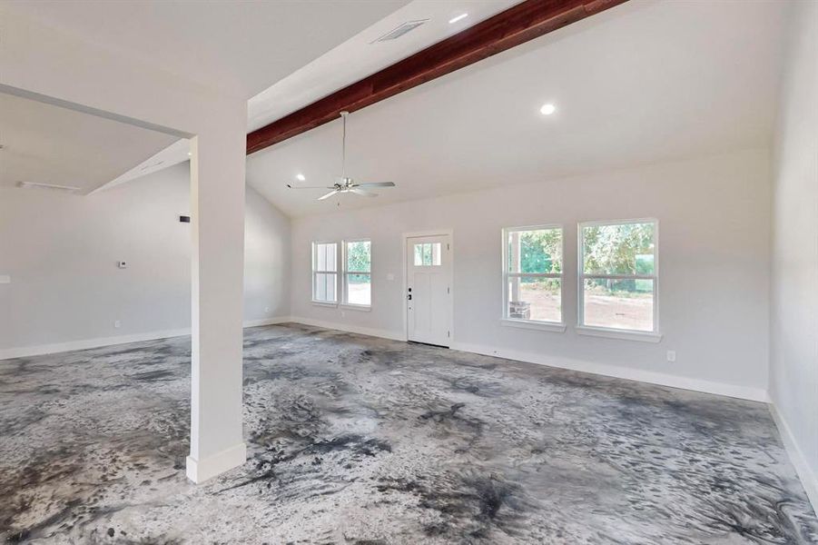 Unfurnished living room featuring vaulted ceiling with beams and ceiling fan