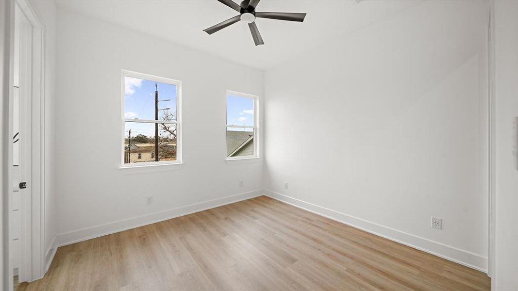 Secondary Bedroom with luxury vinyl plank floors, large windows, a ceiling fan, and a functional walk-in closet along with an en-suite bathroom.