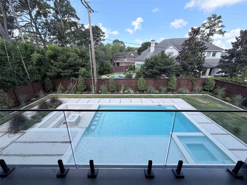 View from balcony with oversized pool and sunken area with gas fire pit
