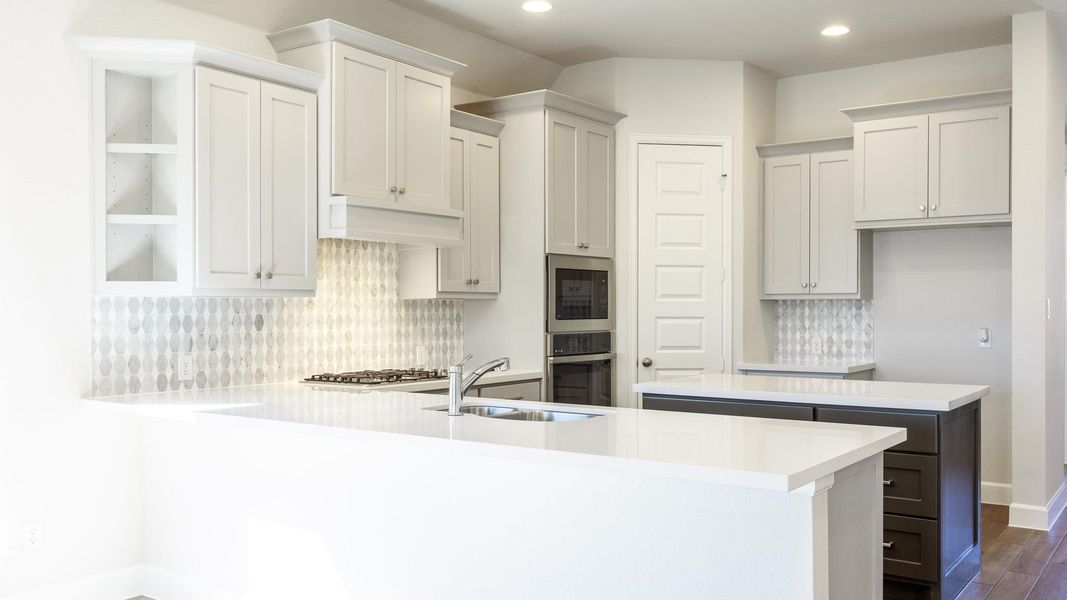 Kitchen featuring a sink, decorative backsplash, recessed lighting, a peninsula, and dark wood-style flooring