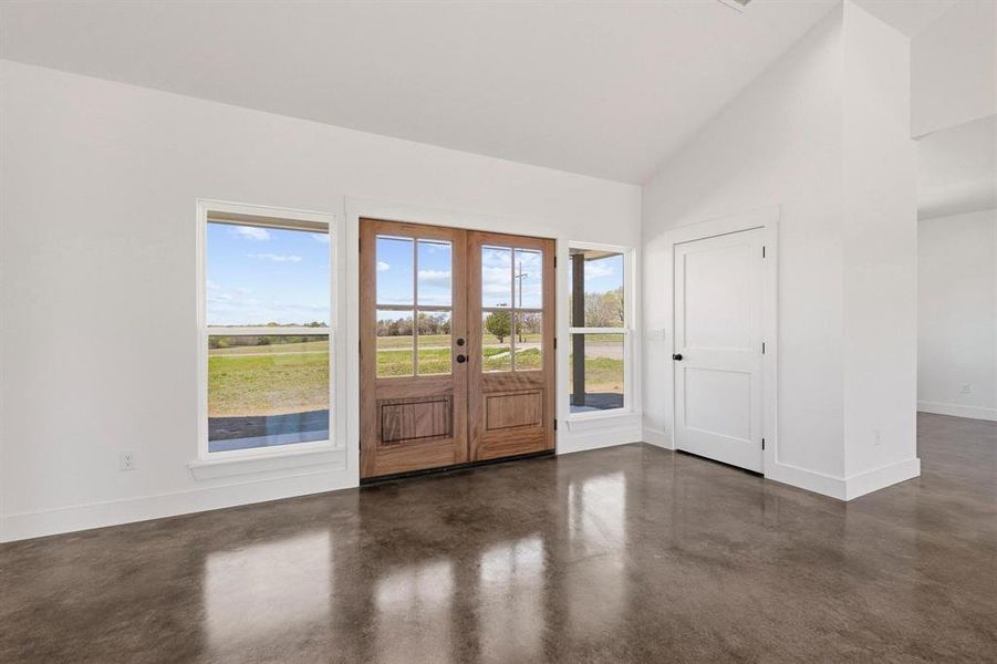 Welcoming entrance with rich wood double doors, polished concrete floors, and large windows offering views of the surrounding landscape