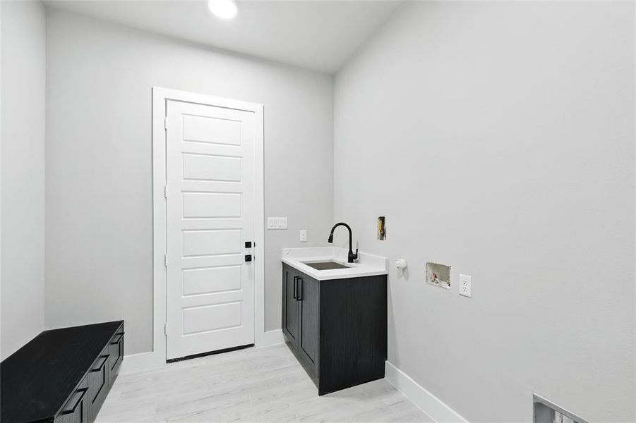 Washroom featuring cabinet space, hookup for a gas dryer, hookup for a washing machine, light wood finished floors, and electric dryer hookup