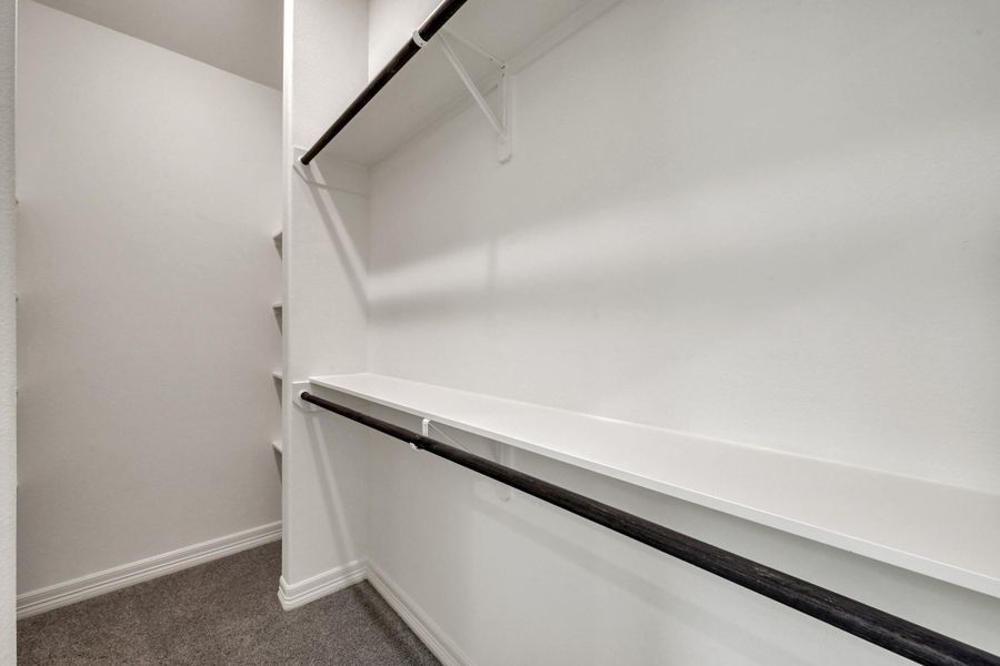 Discover a spacious and well-organized primary walk-in closet, perfect for showcasing your wardrobe in style.