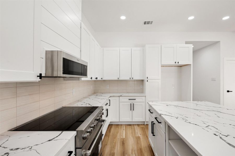 Kitchen featuring light stone counters, electric range, white cabinets, light wood-type flooring, and recessed lighting Kitchen featuring light stone counters, electric range, white cabinets, light wood-type flooring, and recessed lighting