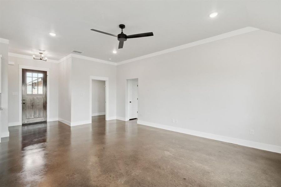 Empty room with ornamental molding, concrete flooring, and ceiling fan