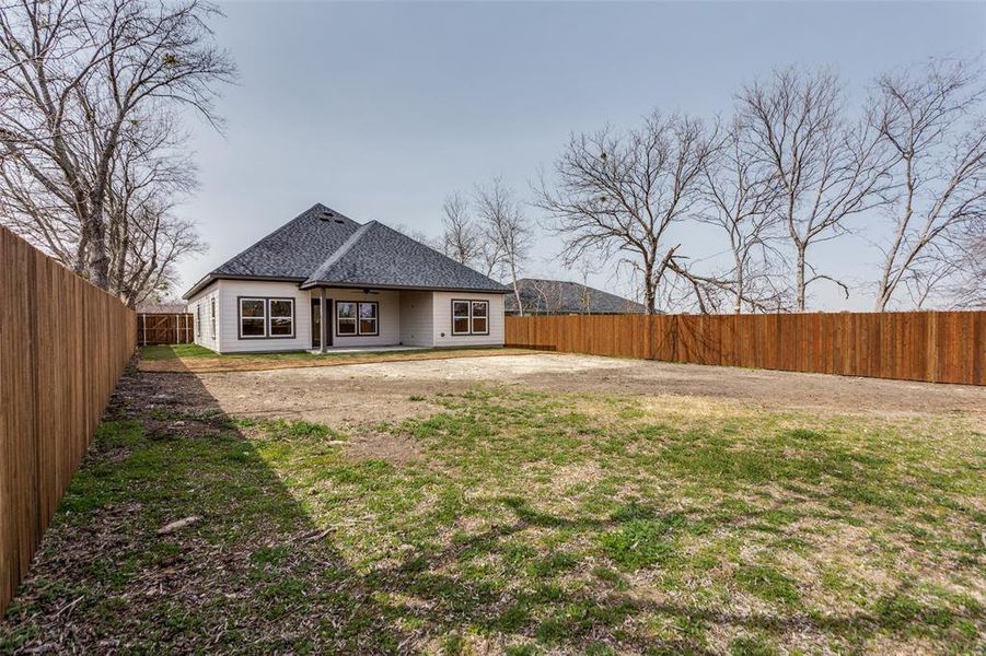 Back of property featuring a fenced backyard, a patio, and roof with shingles