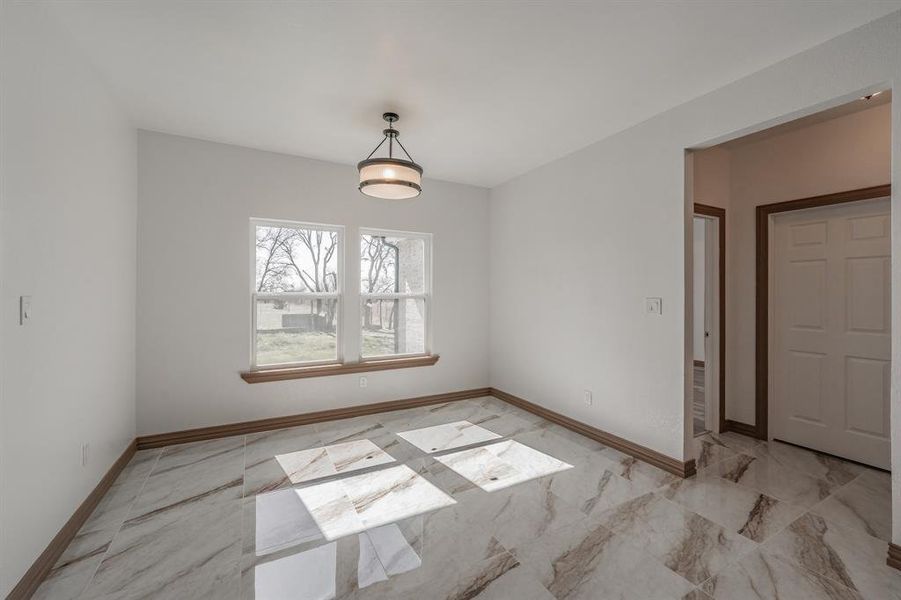 Unfurnished dining area featuring marble finish floor and baseboards