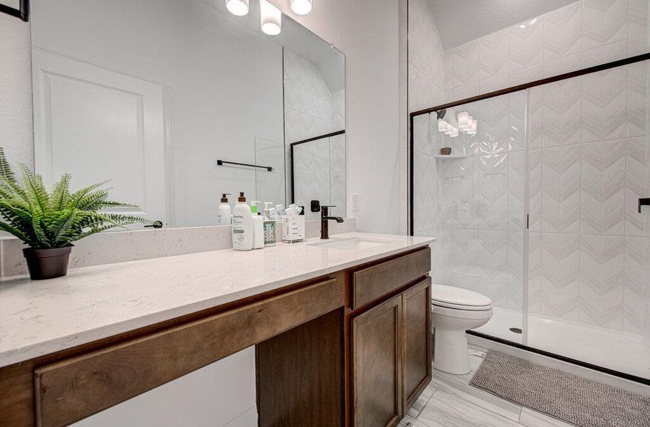 Chevron tiled walls and sleek stone countertops elevate this modern bathroom design. Chevron tiled walls and sleek stone countertops elevate this modern bathroom design.