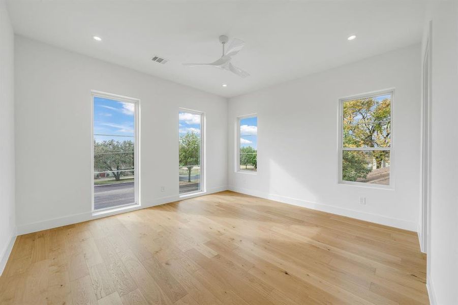 Unfurnished room featuring light wood finished floors, healthy amount of natural light, ceiling fan, and recessed lighting