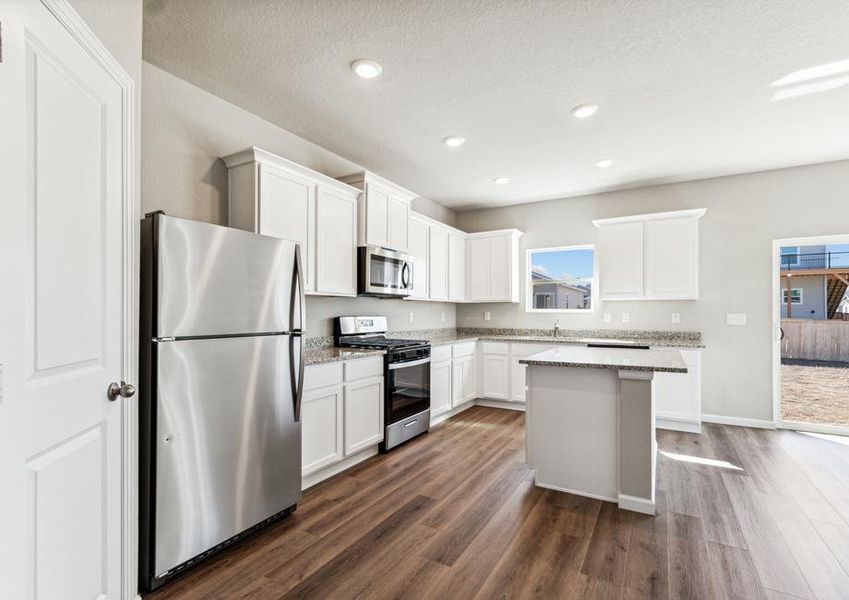 The kitchen has stainless steel appliances and plank flooring.