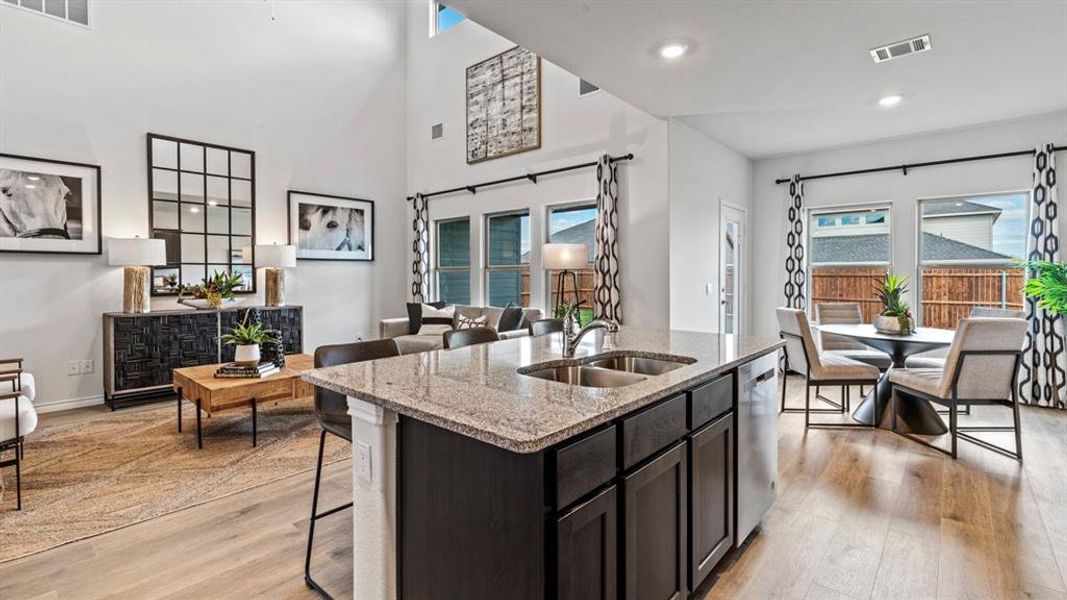 Kitchen island featuring granite countertops, double basin stainless steel sink, and dark wood cabinetry Kitchen island featuring granite countertops, double basin stainless steel sink, and dark wood cabinetry