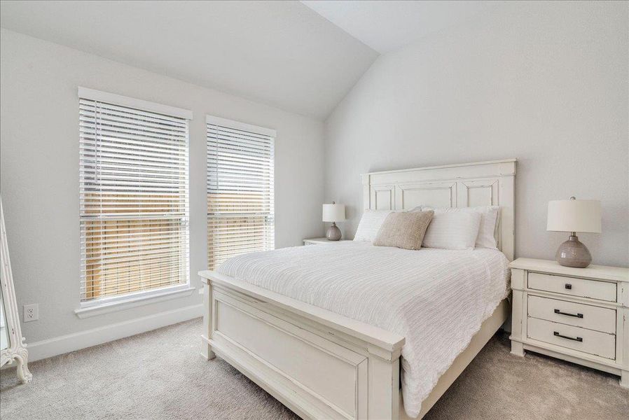 Bedroom featuring lofted ceiling and light colored carpet
