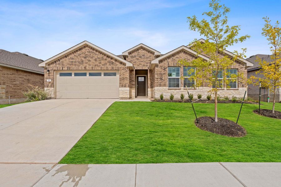 Ranch-style house featuring brick siding, driveway, a front yard, an attached garage, and stone siding Ranch-style house featuring brick siding, driveway, a front yard, an attached garage, and stone siding