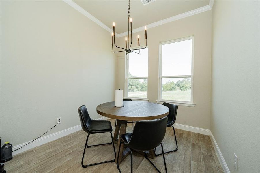 Dining space with light wood-type flooring, crown molding, and a chandelier Dining space with light wood-type flooring, crown molding, and a chandelier
