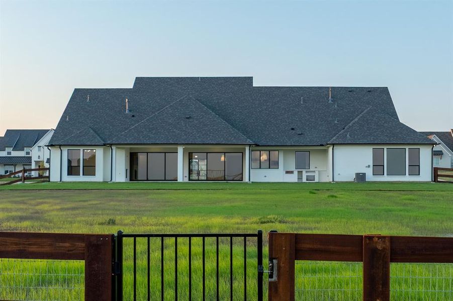 Rear view of property featuring a gate, a patio area, and roof with shingles Rear view of property featuring a gate, a patio area, and roof with shingles
