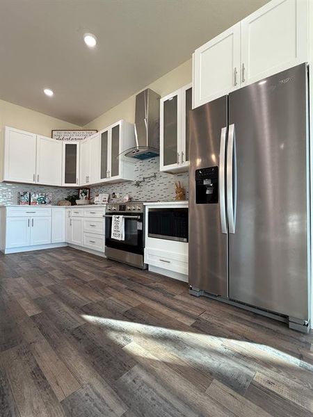 Full view of kitchen and glass hood range and stainless steel hood and pot filler.