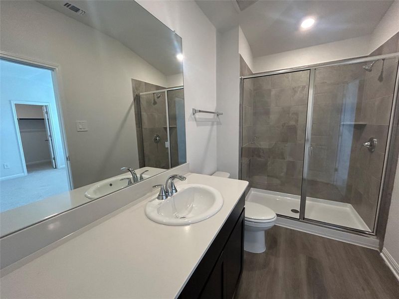 Full bath with vanity, a shower stall, wood finished floors, and lofted ceiling