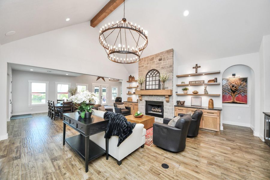 Experience modern elegance in this open-concept living space, featuring a stunning stone fireplace, vaulted ceilings with rustic wood beams, and a grand chandelier. The area seamlessly connects to a cozy dining nook, creating a perfect blend of style and functionality.