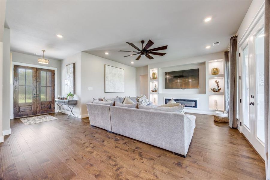 Living room featuring french doors, hardwood / wood-style flooring, recessed lighting, a ceiling fan, and a glass covered fireplace