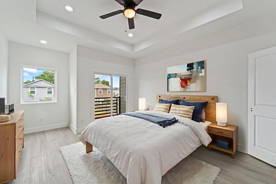 This view of the primary bedroom highlights the large window and a sliding glass door providing access to an exterior balcony.