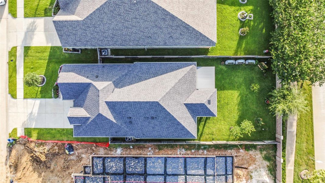 An overhead view of this charming home shows the lushness of the landscaping. The neighborhood maintained trees behind the brick wall provide shade to the backyard.