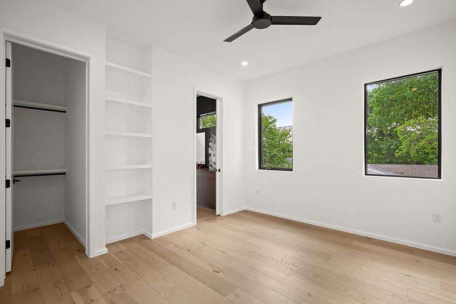 Unfurnished bedroom with light wood-style flooring, connected bathroom, a ceiling fan, recessed lighting, and a spacious closet