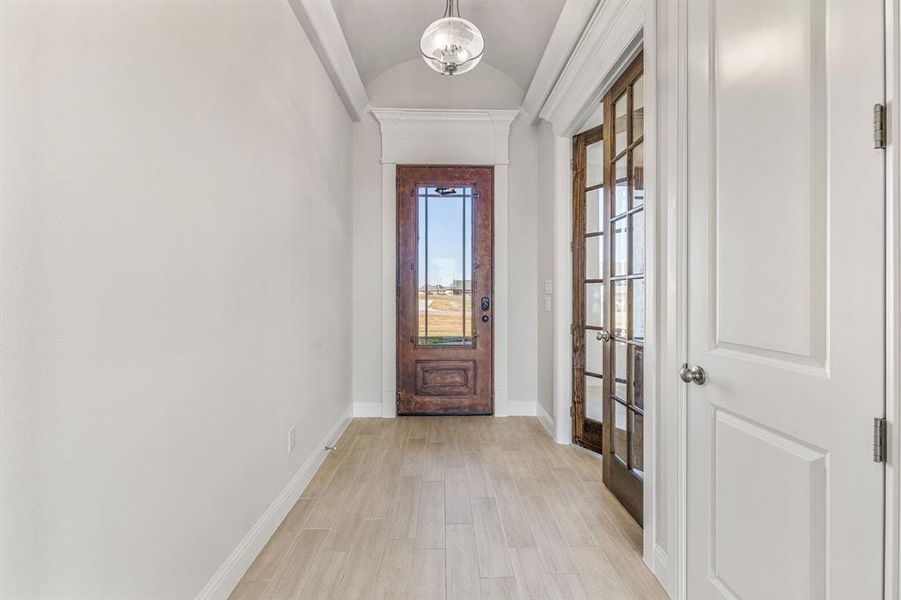 Foyer with lofted ceiling, light wood finished floors, and french doors