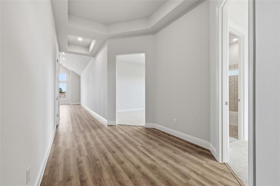 Corridor featuring recessed lighting, light wood finished floors, and a raised ceiling Corridor featuring recessed lighting, light wood finished floors, and a raised ceiling