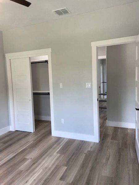 Discover a naturally illuminated bedroom with resilient wood-look flooring and a functional walk-in closet. Discover a naturally illuminated bedroom with resilient wood-look flooring and a functional walk-in closet.